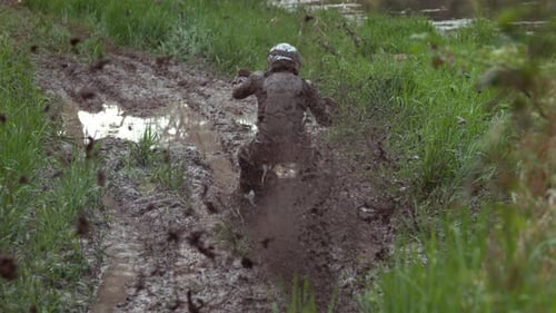 Dirt Bike Rider Splashing Through Muddy Rural Trail