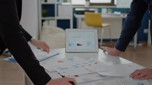 Close Up of Tablet and Papers with Data Charts on Desk