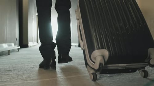 Legs of Businessman Carrying Suitcase in Hotel