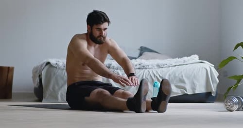 Bearded Man Stretching on Floor at Home