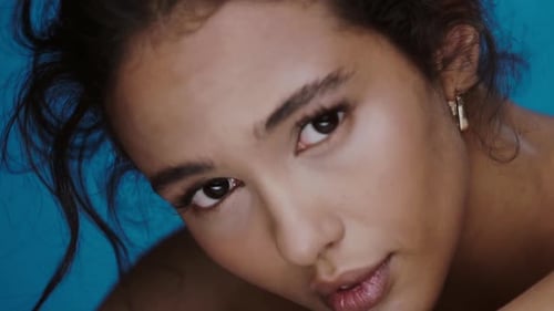 Glamorous Woman with Curly Hair Posing on Blue