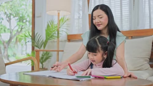 Woman Helping Child Drawing in Home Interior