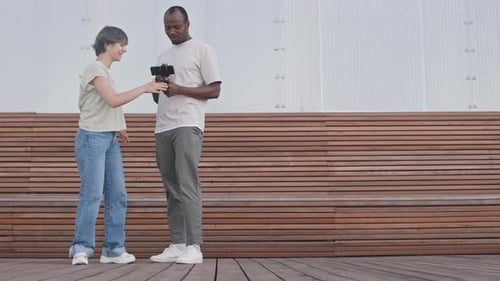 Pareja de influencers viendo y grabando videos de baile al aire libre