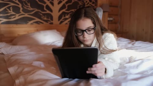 Girl Using Tablet on Bed in Cozy Cabin