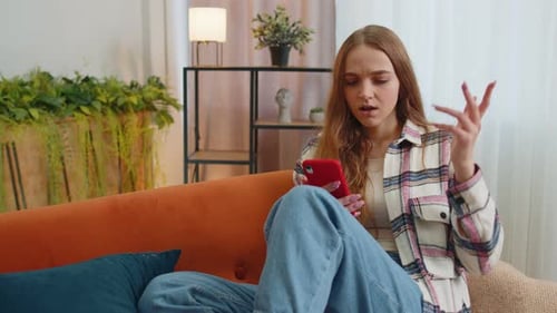 Frustrated Woman Using Smartphone on Sofa at Home