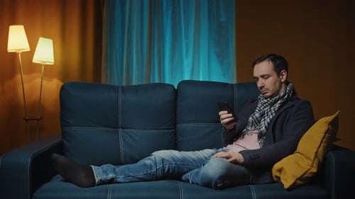 Adult On Couch Using Phone at Home