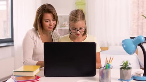 Woman Helping Child with Laptop Homework at Home