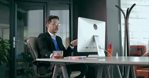 Businessman in Office in Front of Computer Showing Happy Emotions