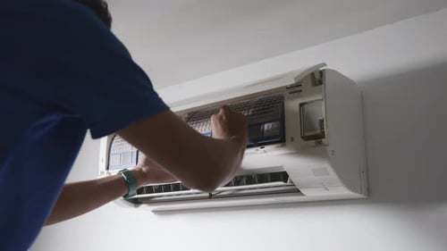 Professional technician male Removing dirty air conditioner filter for wash