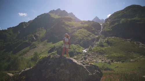Woman Hiker Rests on Rock Overlooking Mountain Landscape