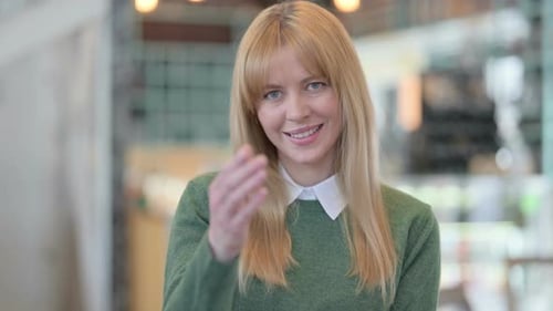Smiling Woman Motions with Hand to Come Here