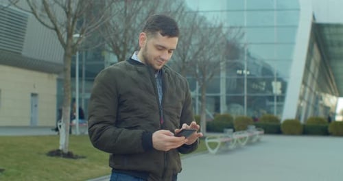 Young Man at the City Street Using Mobile Phone, Typing Text, Chatting with Friends, Man Using