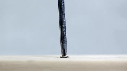 Screwdriver Tightening Screw into Wood Plank Close Up