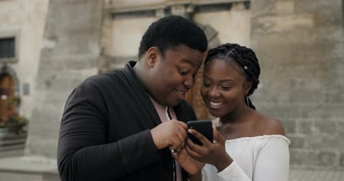 Young Couple Laughing Together Looking at Smartphone