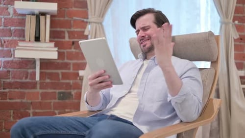 Man Reacts Negatively to Tablet While Sitting