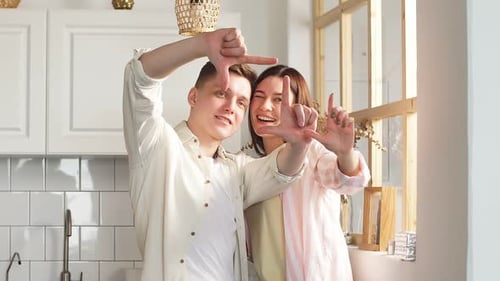 Smiling Couple Creates Finger Frame in Sunny Kitchen