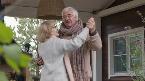 Senior Caucasian Wife and Husband Dancing on Outdoor Terrace