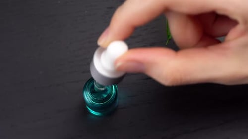 Serum Being Extracted from Teal Glass Dropper Bottle
