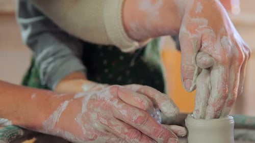 Child Learning Pottery with Adult Hands On