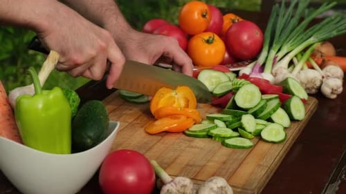 Hands Slicing Fresh Vegetables in Garden Setting