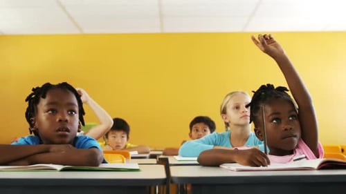 Crianças em idade escolar levantando a mão na sala