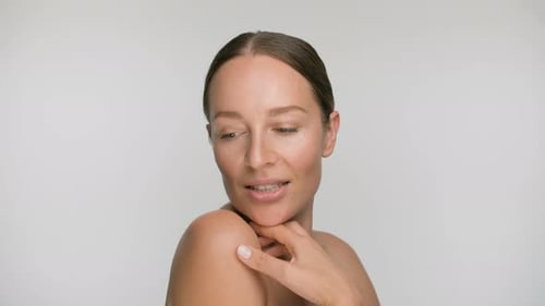 Close-up Beauty Portrait of Young Woman with Smooth Healthy Skin, She Gently Touches Her Face with