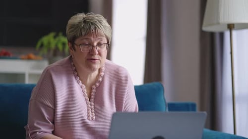 A velha senhora está dando as boas-vindas aos interlocutores por bate-papo por vídeo on-line, comunicando-se por videochamada no laptop com