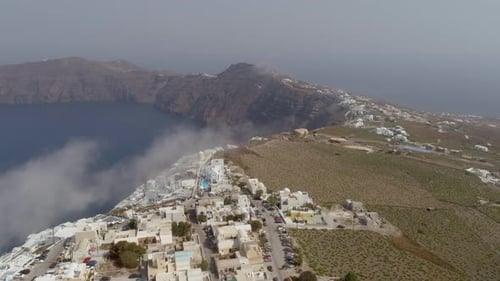 Aerial view of traditional white houses on Santorini island on cloudy day.