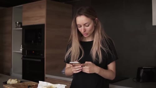 Woman Uses Phone in Modern Kitchen