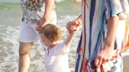 4K Caucasian family parent with little baby son holding hands and walking together on tropical beach