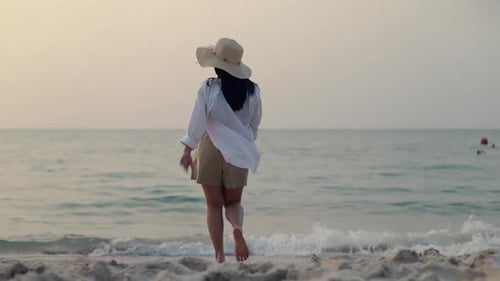 Woman walking on the beach beautiful sunset.