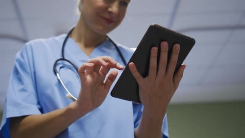 Midsection of portrait of caucasian female doctor using digital tablet in hospital room
