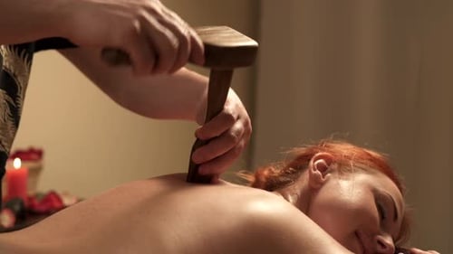 Woman Receiving Massage with Wooden Mallet and Rod