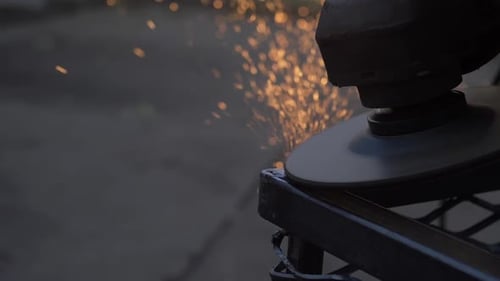 Worker Using Angle Grinder In Factory Hall