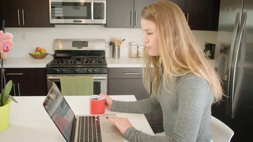 Young Woman Uses Laptop at Kitchen Table