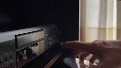Eine Hand legt eine CD in den CD-Player ein