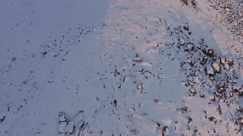 Drone Over Man Hiking Up Mountain Slope In Snow