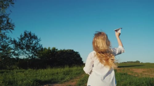 Girl Runs with Paper Airplane on Rural Path
