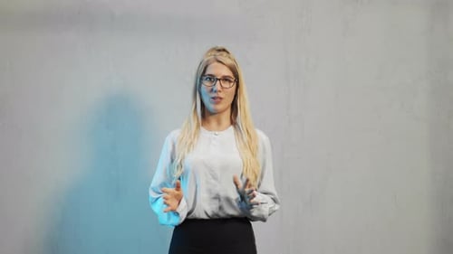 Blonde Woman Talking and Gesturing in Front of Wall