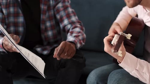 Musicians Collaborate with Guitar and Sheet Music