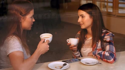Two Women Friends Chatting Over Coffee at Cafe