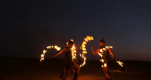Professionelle Künstler zeigen eine Feuershow bei einem Sommerfestival im Sand in Zeitlupe