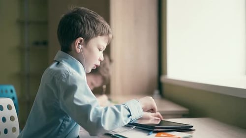 Young Boys Learning Using Tablet and Writing