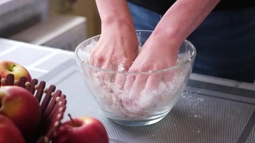 Hands Mixing Dough in Bowl in Kitchen