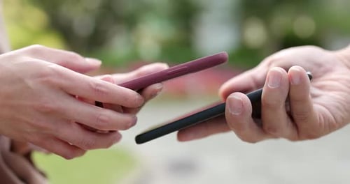 People Exchanging Smartphones Outdoors Close Up
