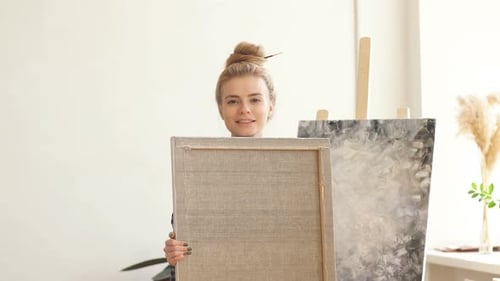 Smiling Woman Holding Blank Canvas in Art Studio