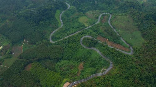 Aerial view over a winding road in the mountains of a tropical forest, Thailand.