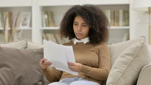Woman Reads Papers on Sofa at Home