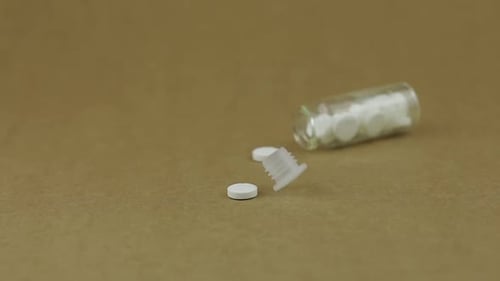 Glass Jar Falls and White Round Pills Fall Out of It. Slow Motion