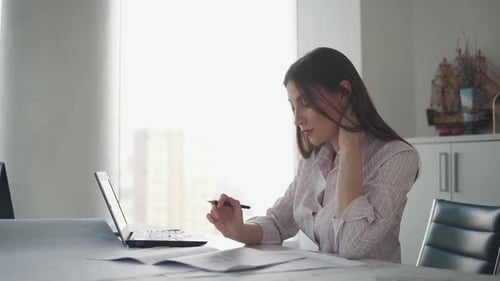Attractive Girl Working with Documents Drawings Sitting at the Table in the Office